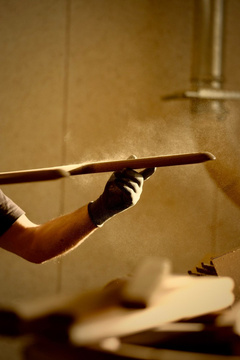 Craftsman holding a length of timber in warm workshop light